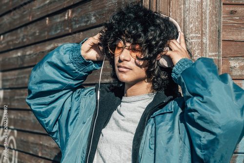 Latino Hispanic teenager with headphones on the wall in the street