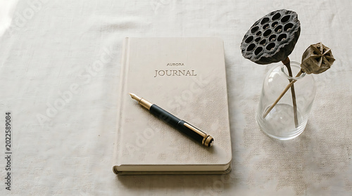 Journal and pen on table with decorative flowers in glass vase transparent background