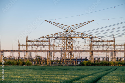Foto Electrical substation with extensive high-voltage power grid infrastructure in rural landscape