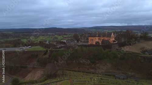 Stirling Scotland city skyline drone flyover and mountains in the distance. Clouds cover the sky, creating an atmosphere in the Scottish highlands