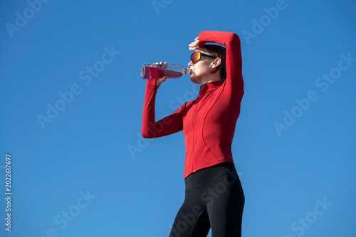 Sporty woman drinking water after exercise outdoors