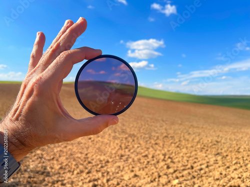 Billede på lærred Close up of a photographer's hand holding a round polarizing filter showing the