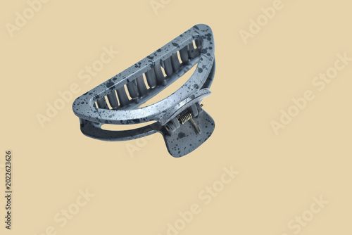 Gray matte hair claw clip with a spotted pattern on a brown background.