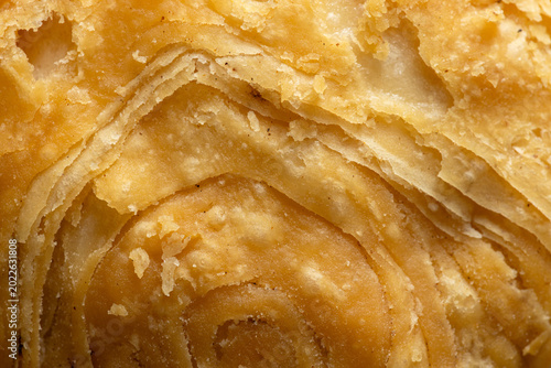 Macro texture of crispy layered puff pastry dough background,Extreme close-up texture of golden brown curry puff pastry, showing detailed crispy layers and crunchy surface background.