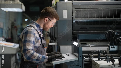 Print technician operating industrial printing press machine