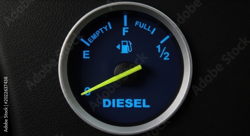 Closeup of a diesel fuel gauge with the needle pointing to empty on a black leather background