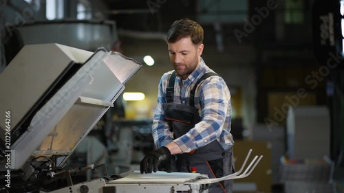Printing house worker operating industrial offset machine
