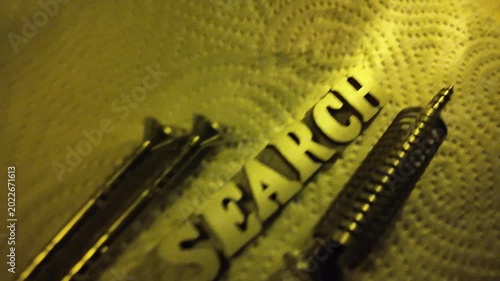 Wooden letters spelling WEB are scattered with metallic components and illuminated by yellow light.