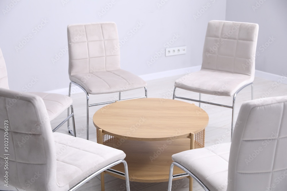 Fototapeta premium Stylish light gray chairs and wooden table indoors, closeup