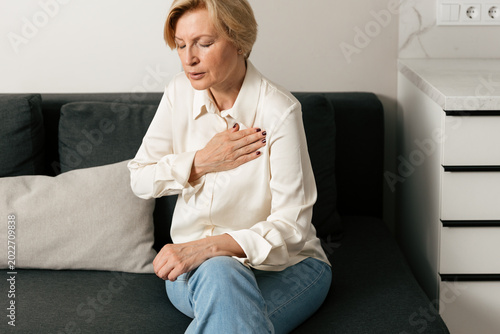 Mature woman experiencing chest pain and heavy breathing