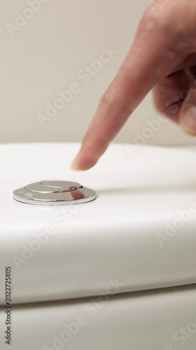 Male hand pushing a button to flush a close tool a bathroom toilet.