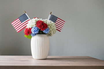 Patriotic flower bouquet with American flags in white vase on table