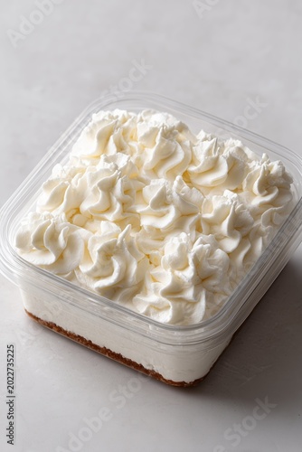 Square container filled with delectable cream cheese dessert, topped with fluffy, piped swirls of whipped cream.