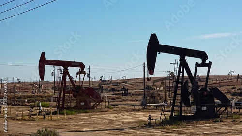 Oil Pump Jacks In Wide Industrial Field, documentary energy video frame with many wells, dry terrain and power lines