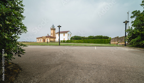 Photos A historic lighthouse and adjacent building, stands prominently on a green lawn