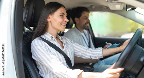 Foto Cheerful confident pretty young woman sitting inside car with man instructor by