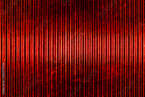 Macro shot of classic retro automobile red rear light lens. Textured ribbed glass surface with scratches creates a vibrant vintage abstract background