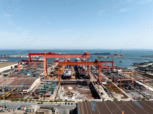 Billede på lærred Large shipyard port operation scene panoramic view with cranes and vessel constr