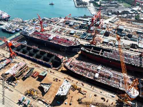 Картината върху платно Aerial view of large ship construction site in shipyard with cranes and hull sec