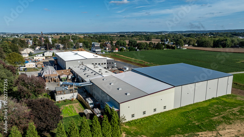 Fotografija A large industrial building sits next to smaller structures and fields