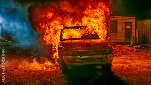 фотографія A truck is on fire at night in an industrial area