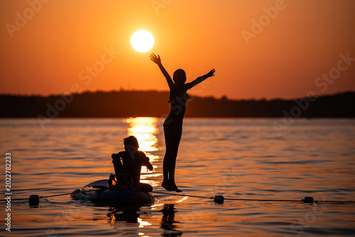 Children jumping and playing in lake at sunset