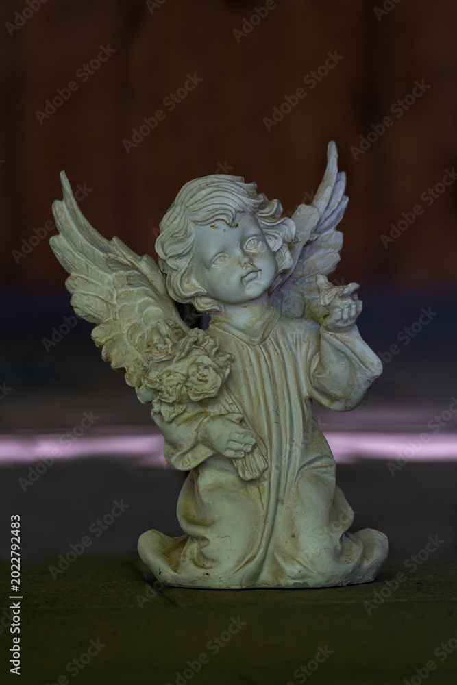 Fototapeta premium Ceramic cherub angel figurine on the floor inside a church interior.