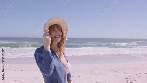 Joyful young woman with straw hat at summer beach