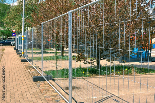 Canvas Print Temporary metal mesh fencing on a city sidewalk for event security