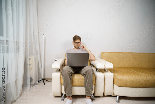 Tableau sur toile An adult man works from home, sitting on the couch