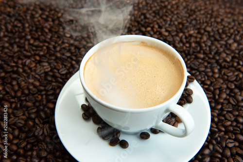 Premium dark roast arabica coffee beans with cozy cup of warm steaming and delicious coffee 