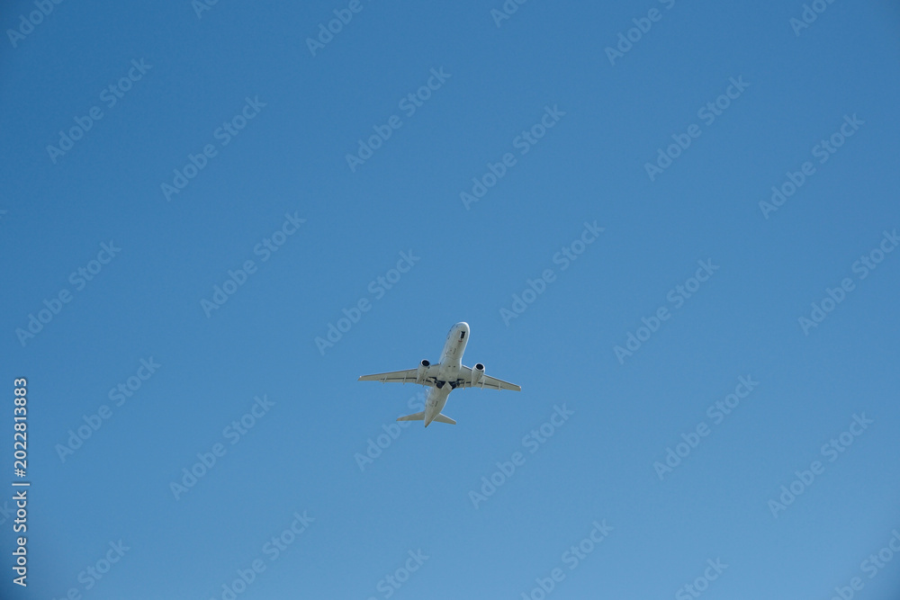 Obraz premium White passenger airplane climbing after takeoff against a clear blue sky. Travel concept