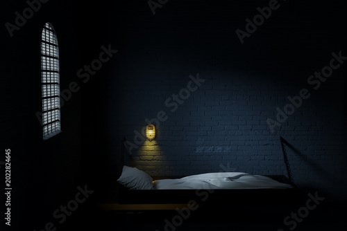 Photography 3D Rendering of old prison cell with light and bed from side view