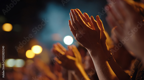 Audience Hands Raised in Applause at a Live Event, Concert, or Performance in a Dark Venue with Bright Stage Lights and Bokeh