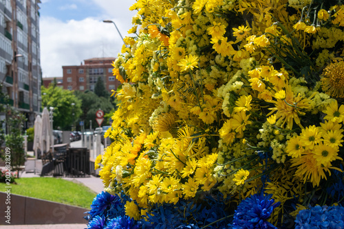 Gran arreglo de flores amarillas y azules expuesto en una calle urbana