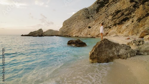 Woman standing on rock by secluded beach during golden hour in Kefalonia Greece