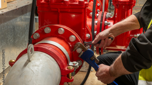 Canvastavla Fire system and specialist sprinkler engineer using wrench and ratchet to tighten a red pipe flange