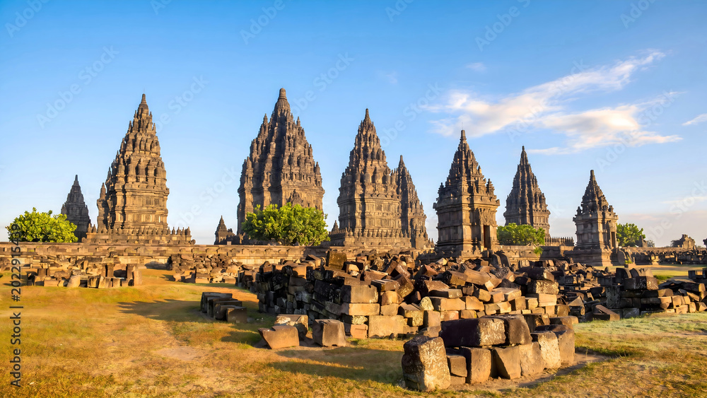 Fototapeta premium Ancient Hindu temple complex with tiered spires and stone ruins under blue sky