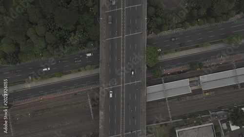Aerial top down view of highway overpass crossing city roads and railway tracks with moving traffic