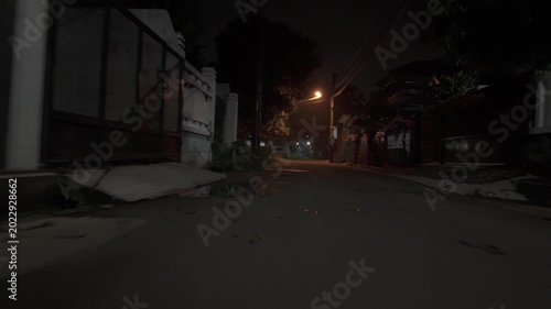 Low angle driving view through a quiet suburban street at night with dim streetlights