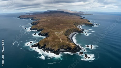 Aerial View of Rugged Coastal Island with Crashing Waves and Dramatic Sky.