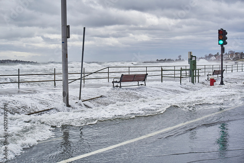 Photos Storm surge causing water to go over the seawall and flood the sidewalk and street while causing damage