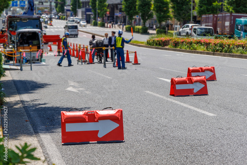 道路工事現場の交通規制と矢印方向板、歩行者を誘導する人