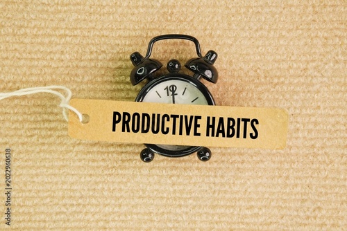 Alarm clock and paper tag with the word productive habits. daily routines that optimize your time, focus, and energy without leading to burnout. Instead of just working longer