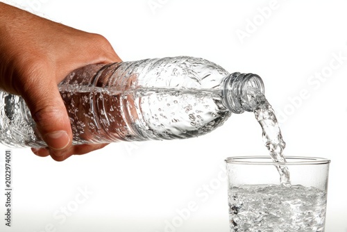 Hand Pouring Fresh Water from Bottle into Clear Glass Cup
