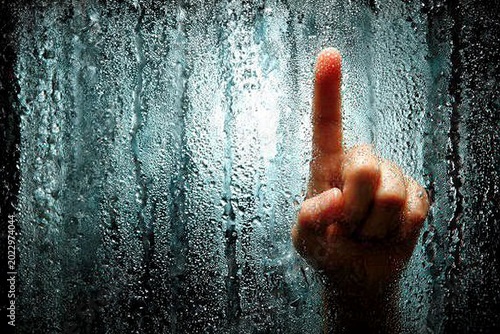 Hand Gesture of a Finger Pointing Up Against a Foggy Glass Surface