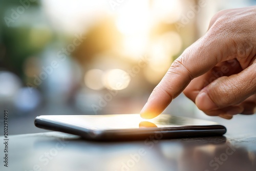 Person Using Smartphone with Finger Touching Screen in Sunlight