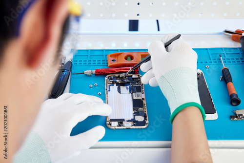 Tableau sur toile Technician repairing disassembled smartphone on electronics workbench