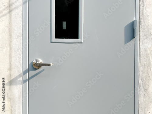 Industrial steel security door entrance with modern hardware and bright sunlight shadows.