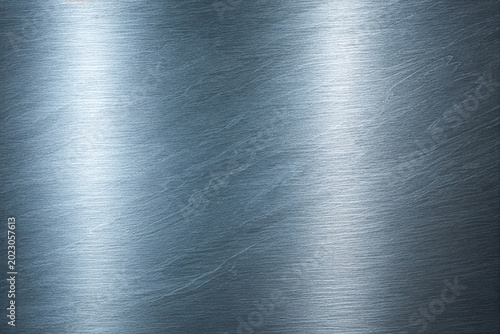 Realistic brushed metal texture with polished stainless steel finish. Industrial silver metallic background featuring fine hairline scratches, smooth reflections, and premium steel surface details.